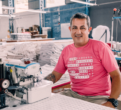 homem sentado atrás de uma máquina de costura e sorrindo